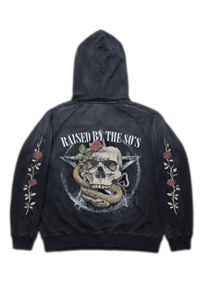 Vintage washed black streetwear hoodie with raised by the 80s back graphic featuring skull, snake and rose design with floral sleeve prints on a clean studio background.