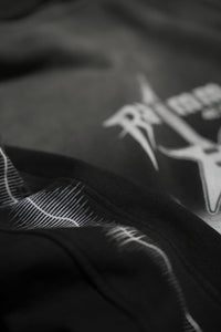 Close-up detail of a vintage washed black streetwear hoodie showing fabric texture and electric guitar print with lightning sleeve graphics.