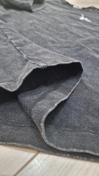 Iron Stage t-shirt in washed black streetwear style showcasing fabric detail and vintage texture in a close-up view.