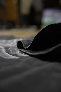 Vintage washed black streetwear t-shirt with fabric texture detail and soft cotton material shown in a close-up view.