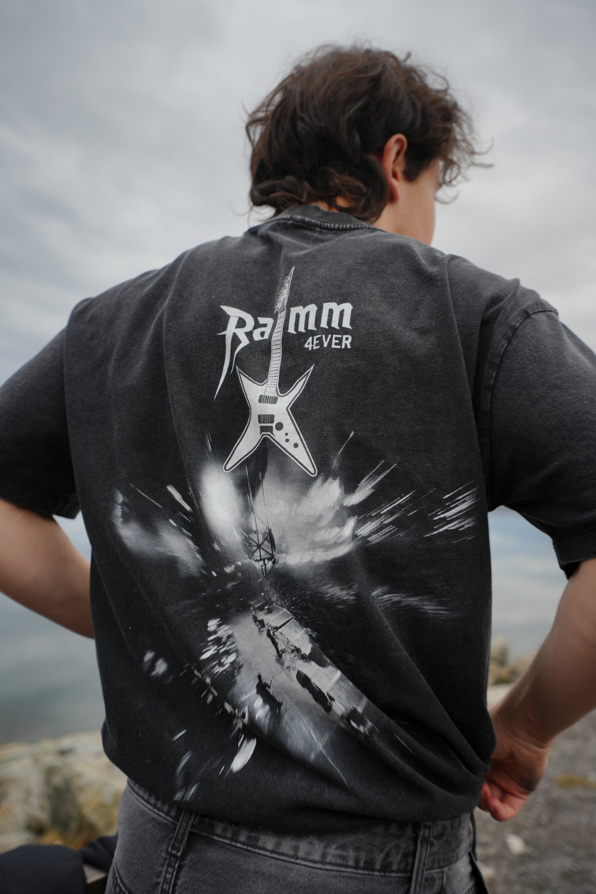 Iron Stage t-shirt in washed black streetwear style with a bold back print, worn outdoors.