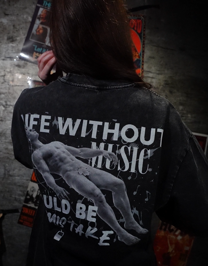 Vintage washed black streetwear t-shirt with life without music would be a mistake back graphic and artistic figure print shown in lifestyle setting.