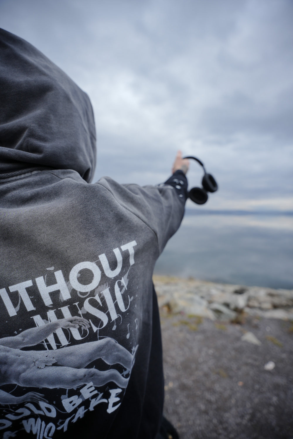 Vintage washed black streetwear hoodie with life without music would be a mistake graphic and artistic figure print shown in an outdoor lifestyle setting.