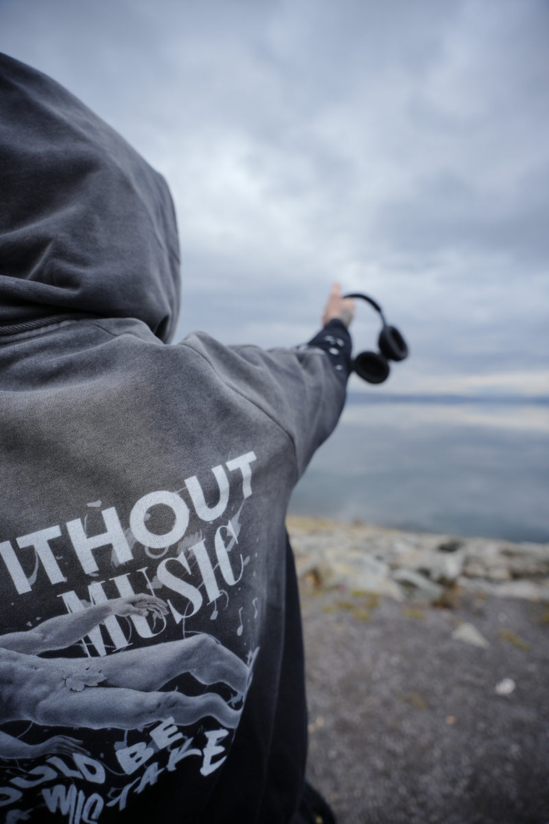 Vintage washed black streetwear hoodie with life without music would be a mistake graphic and artistic figure print shown in an outdoor lifestyle setting.
